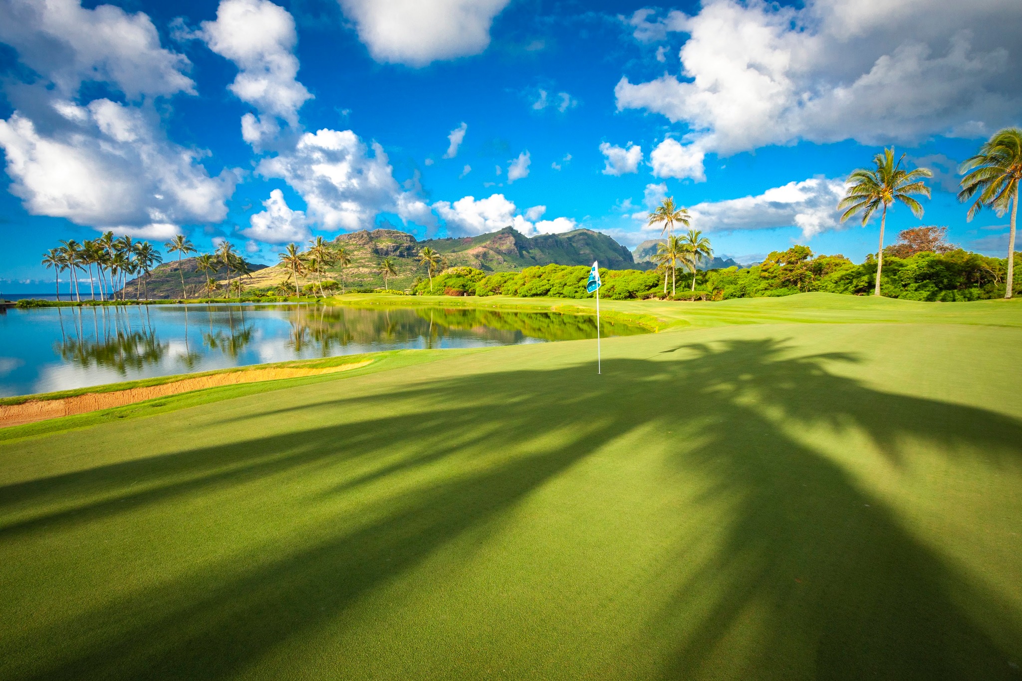 The Ocean Course at Hokalua with water sits against a very blue sky with some clouds.