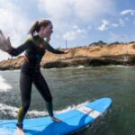 A girl in a wetsuit surfs on a blue board.