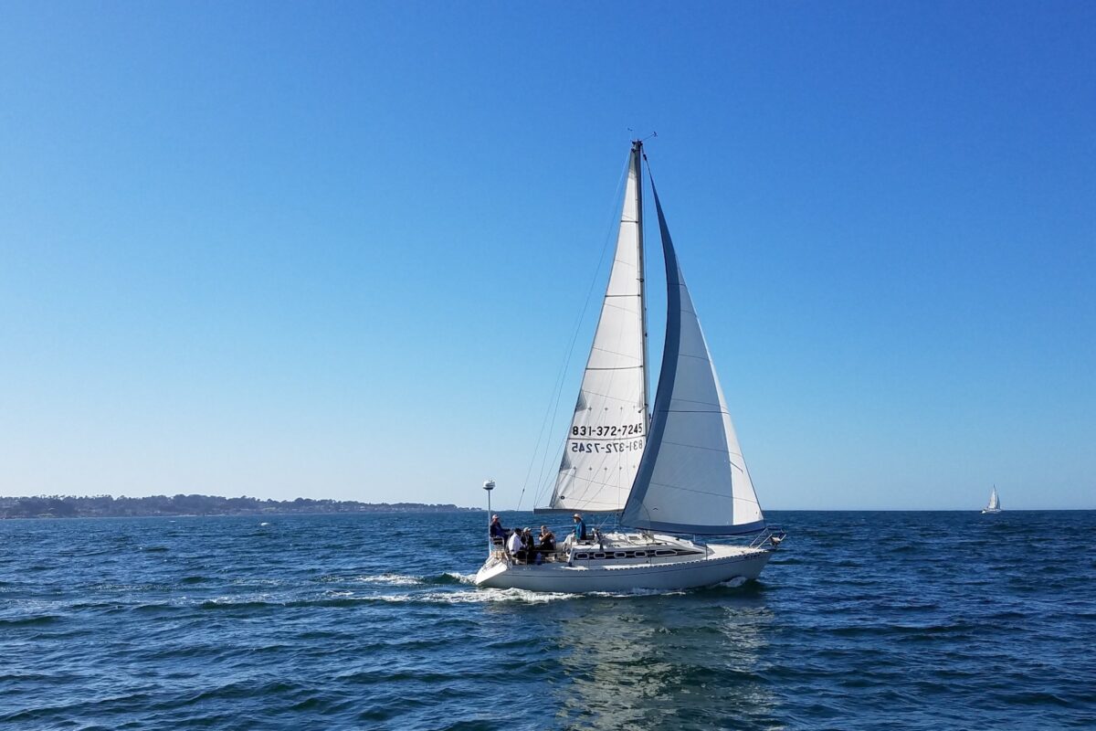 A sailboat sits on the water against a very blue sky.