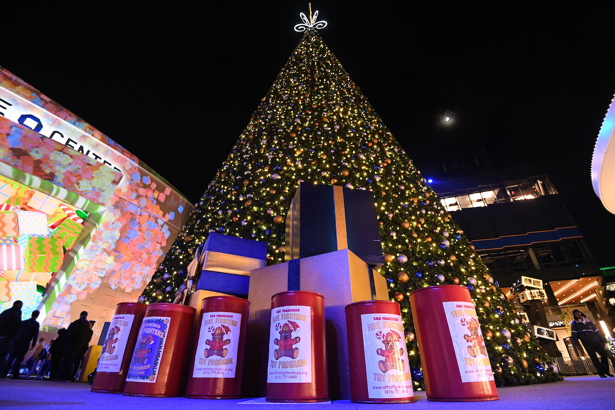 A christmas tree with large presents underneath, seen at night at the Thrive City Christmas Tree Lighting