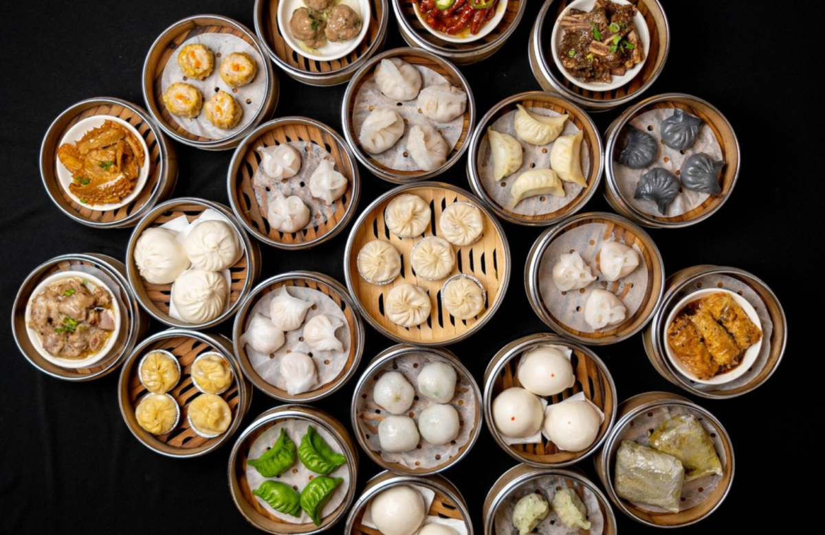 Many steamers with a variety of dim sum types against a black background.