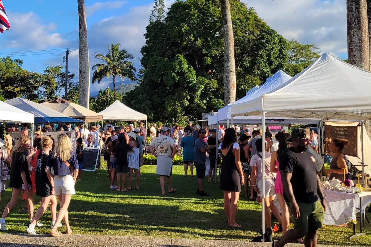 White tents crowded with visitors at each are set up on a grassy area.