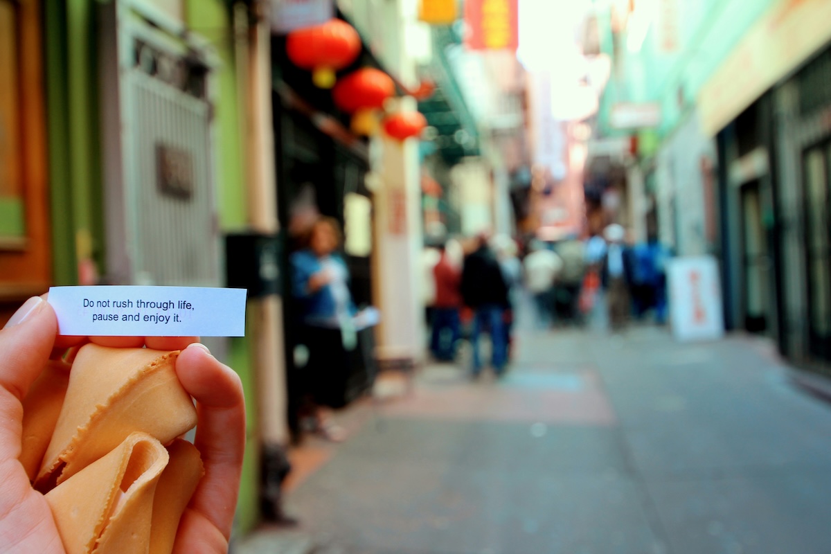 Person holding fortune cookie fortune saying "Do not rush through life, pause and enjoy it"