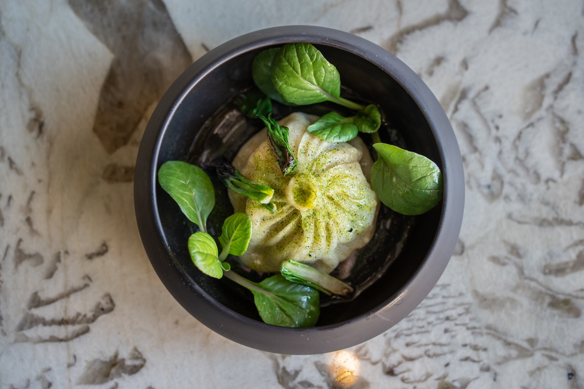 A large dumpling with green sauce and leaves from Mister Jiu's restaurant in San Francisco