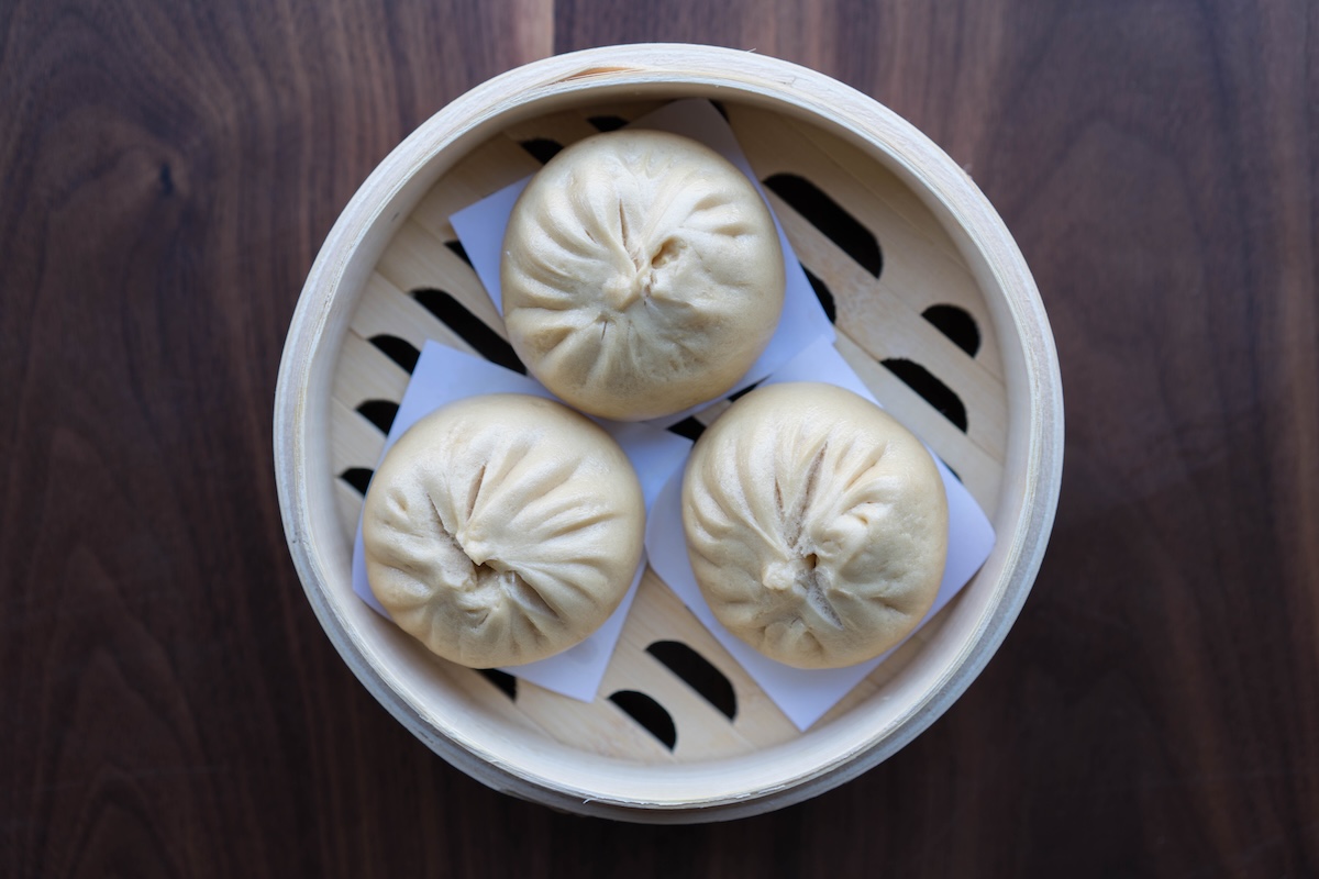 A steamer with three chia siu bao, also known as barbecue pork buns.