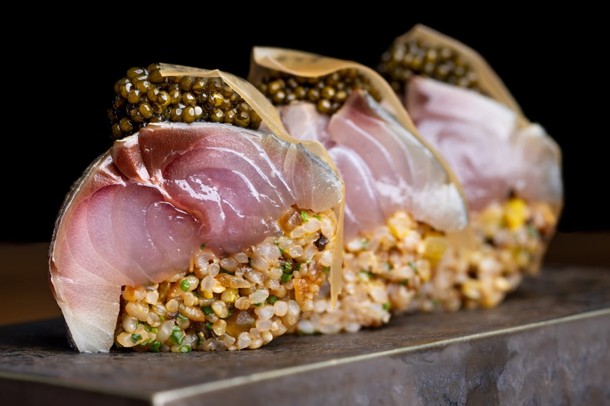 Three slices of fancy sushi, featuring rice, sliced fish and caviar.