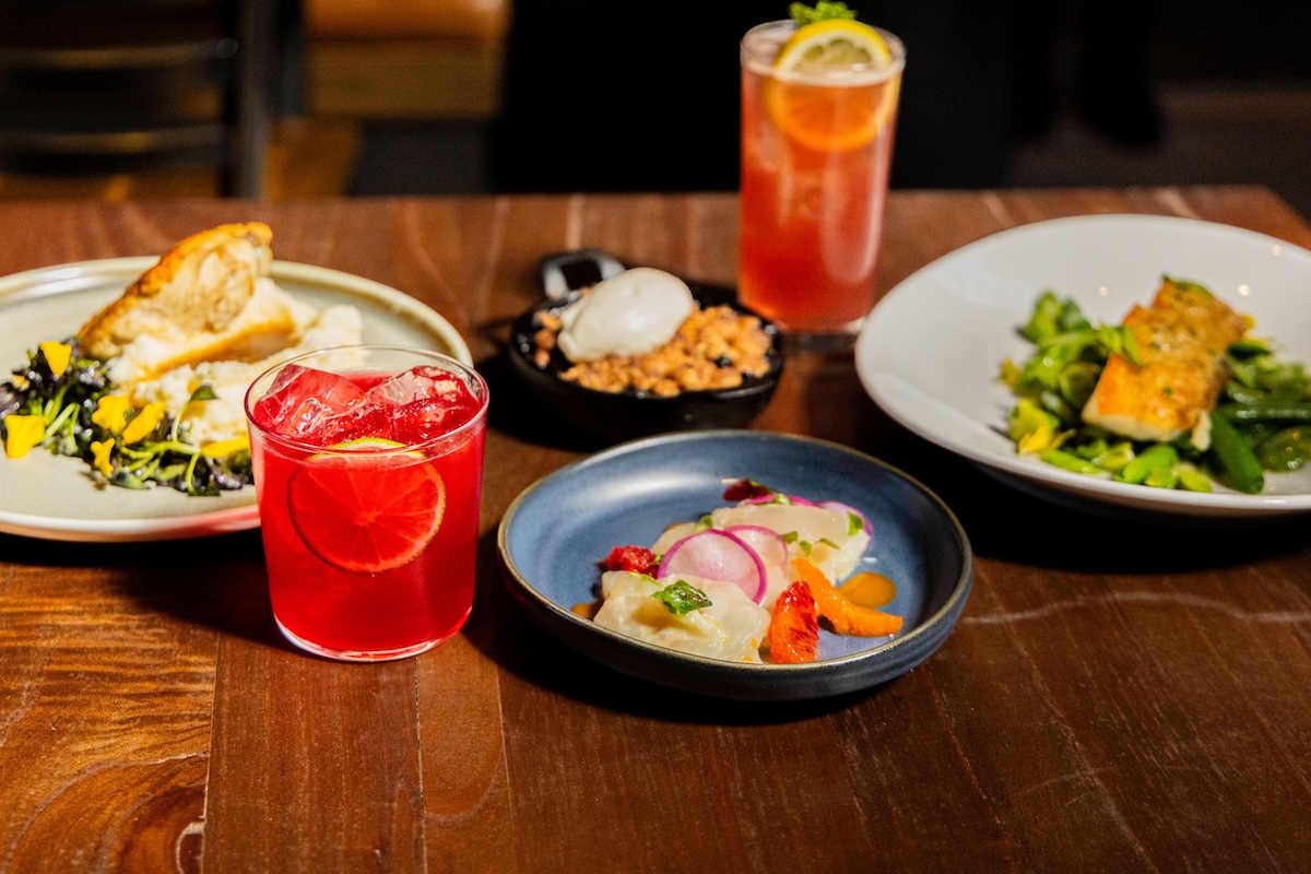 A table spread with plates of various foods and beverages.