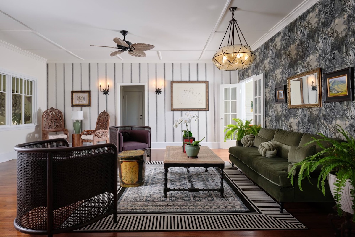 A hotel lobby with a black and white rug, green couch, black seat, coffee table and shiplap walls.