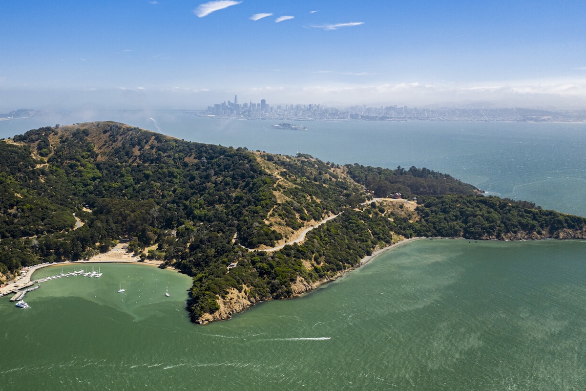 An aerial view of Angel Island, with green waters and a view of the city skyline.