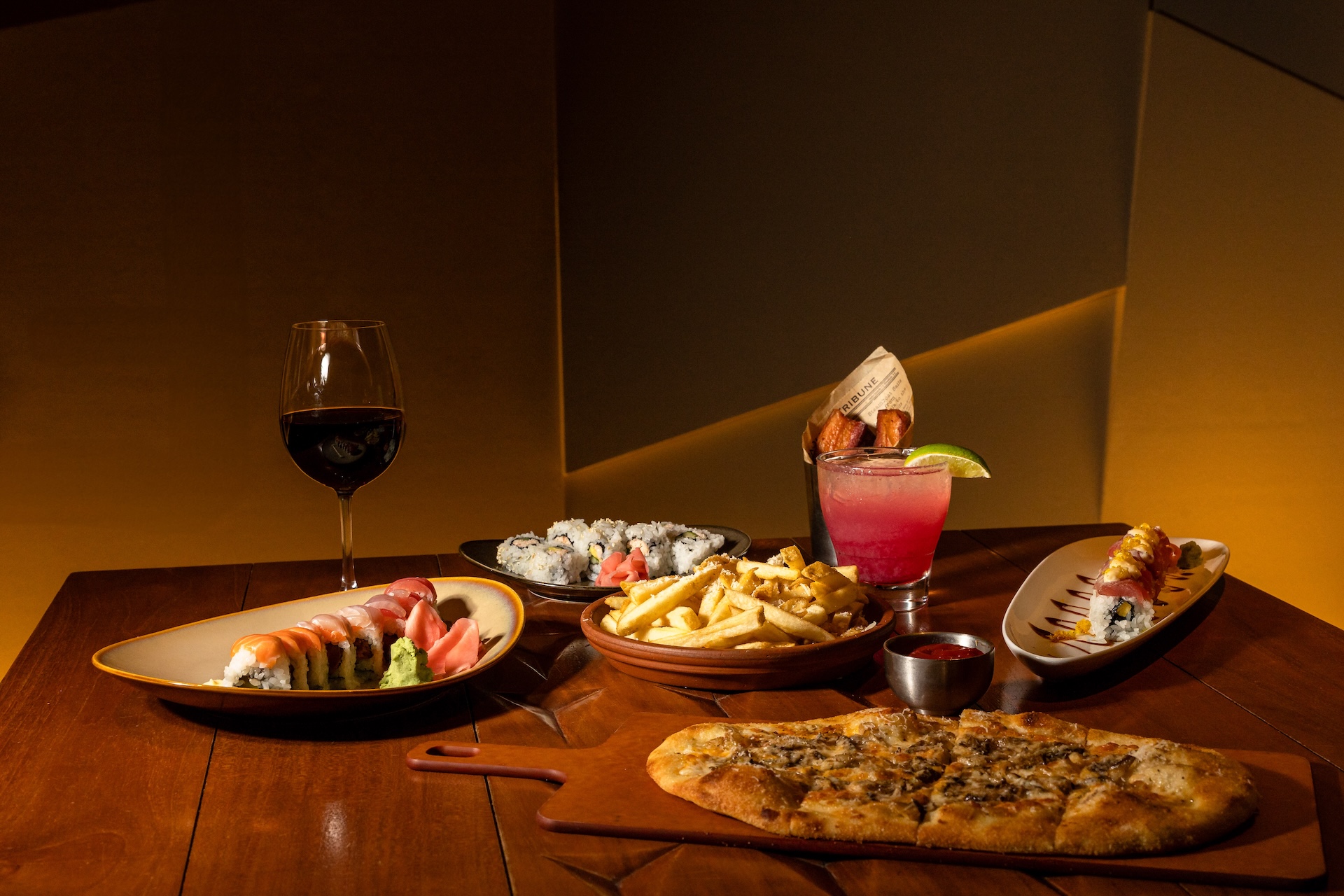 A table with plates of food, cocktails and wine.