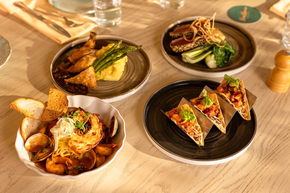 Four bowls of food including poke tacos, a shellfish dish, mashed potatoes and more.