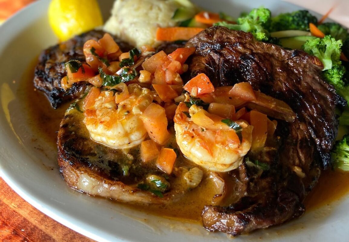 A plate with shrimp, veggies, rice and more.