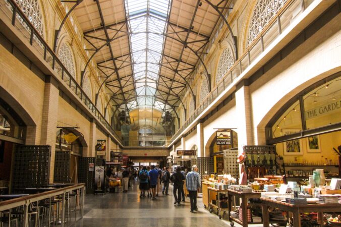 An interior shot of the SF Ferry Building, with tall vaulted ceilings and people walking to visit the various shops.