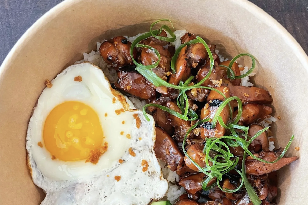 A bowl with mushrooms in a sauce topped with green onion and a fried egg.