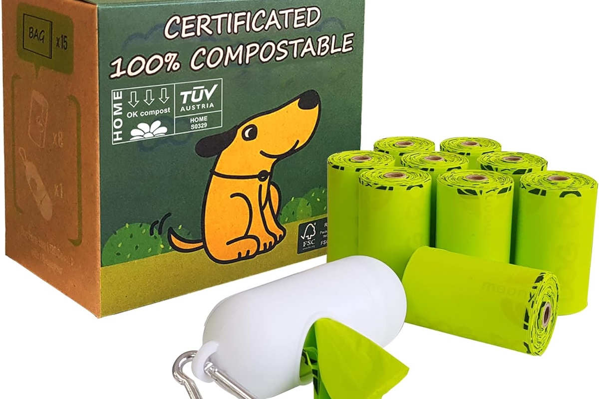 A box with a graphic of a dog and writing that says "Certified 100% Compostable" and rolls of green dog poop bags and a white dispenser next to it.