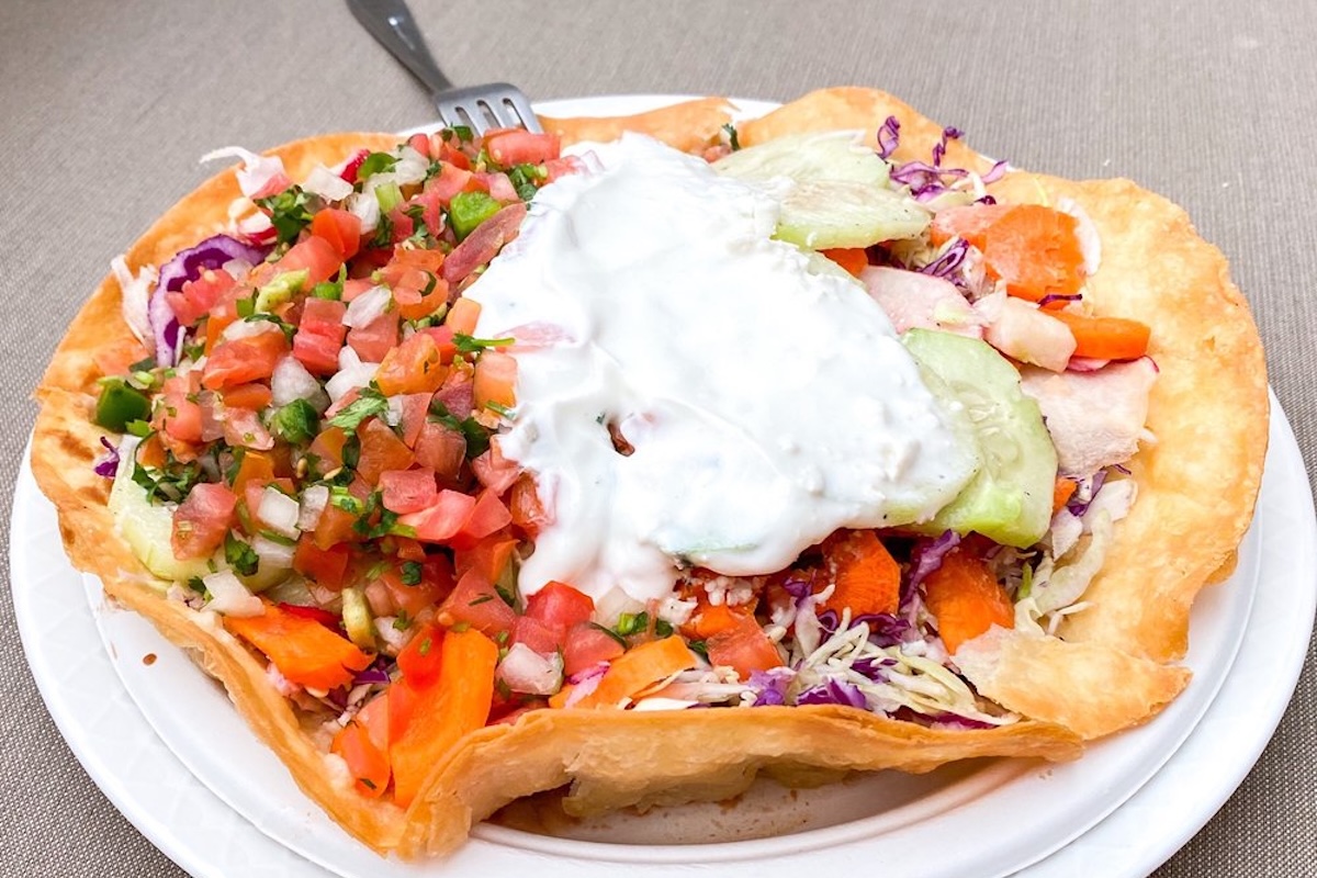 A fried flour tortilla topped with pico de gallo, veggies and sour cream.