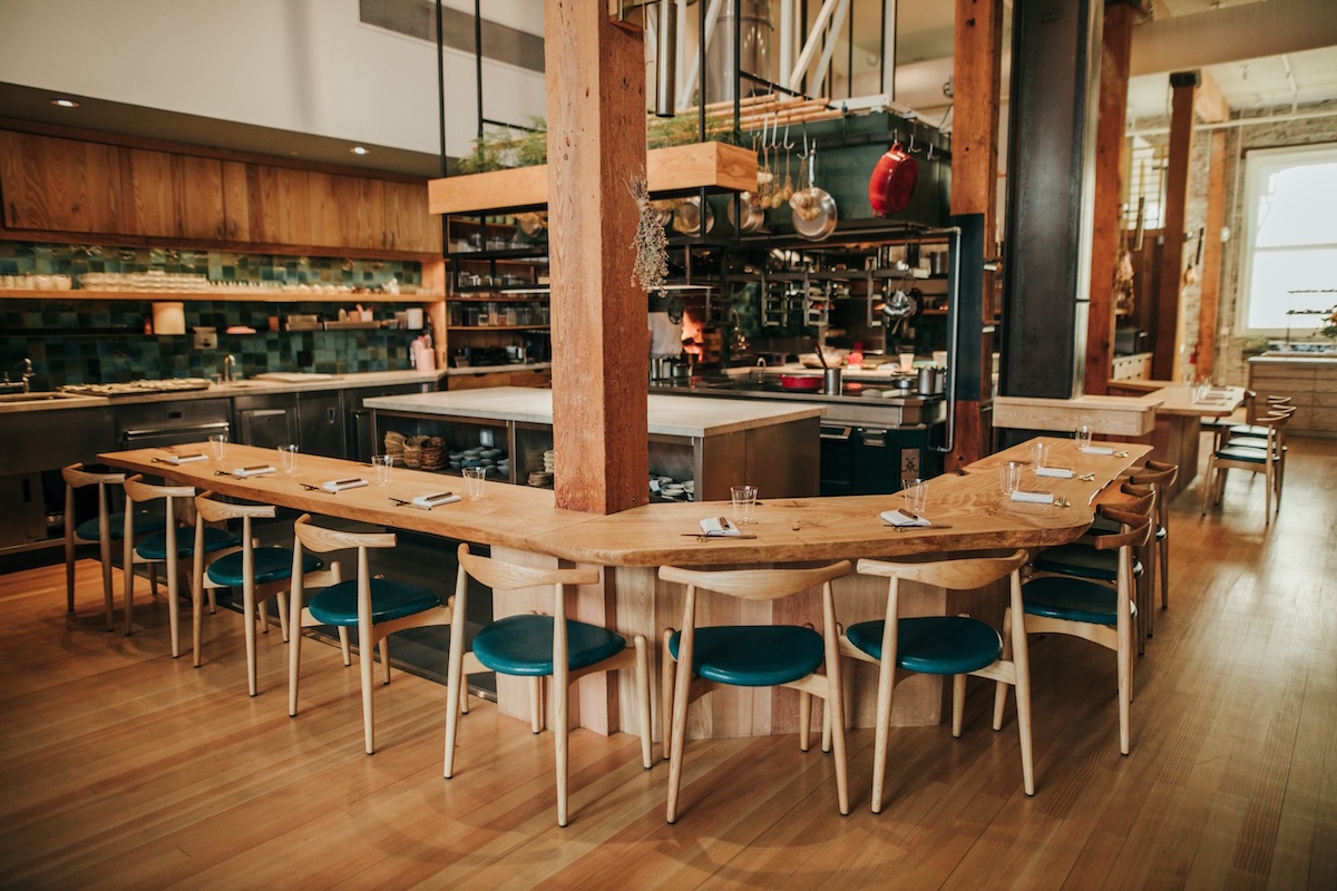 A bar wraps around a few vertical wooden beams as chairs line the sides.