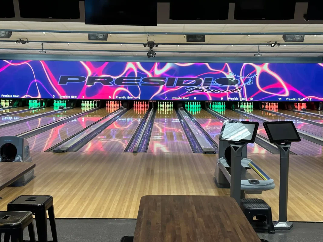A bowling alley with neon purple and pink backdrop above the pins.