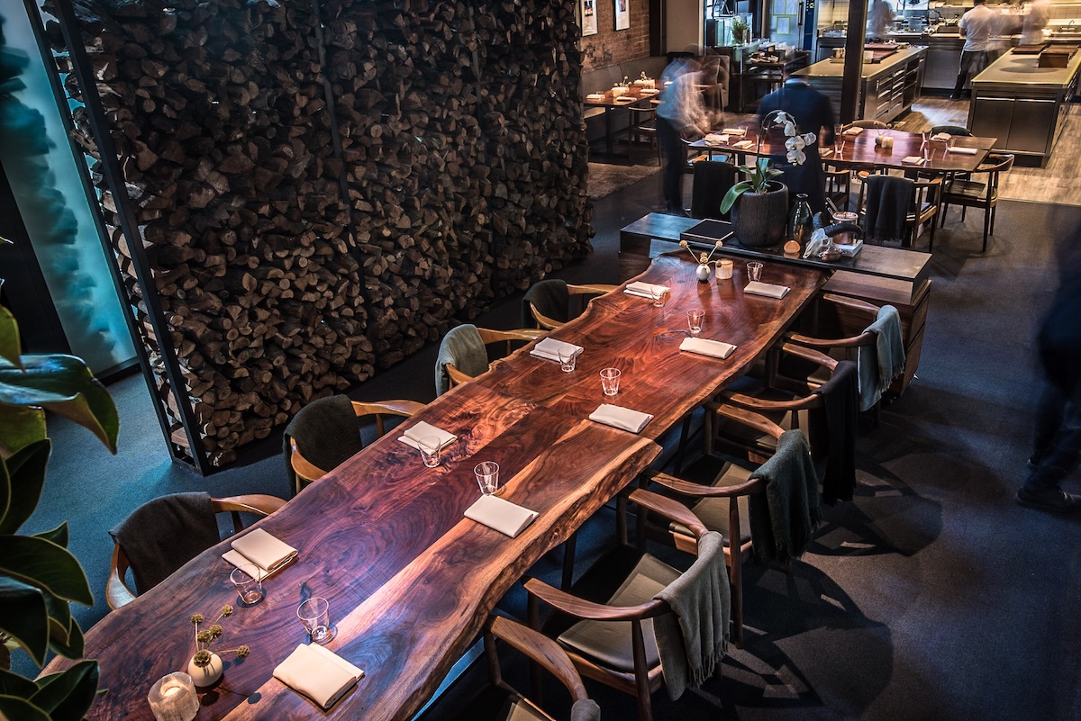 An aerial shot of a long wood table with chair all around it.