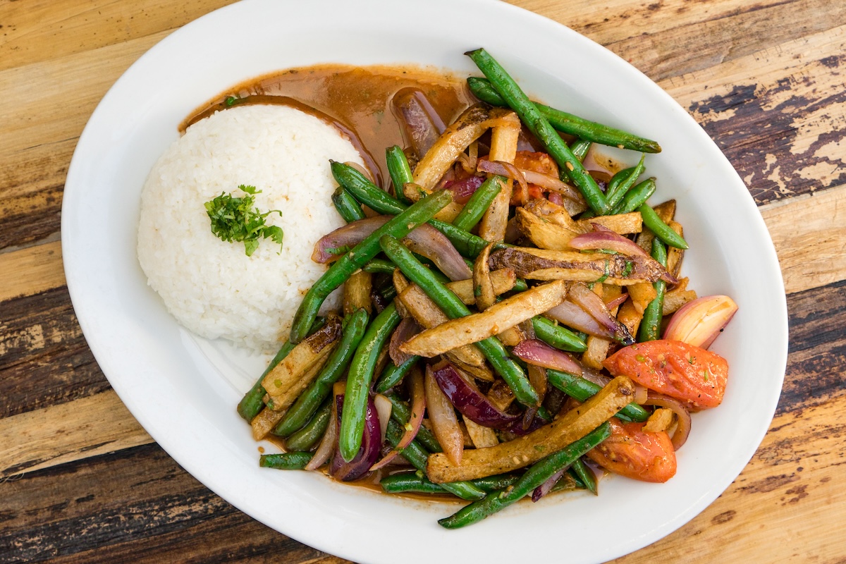 A plate with beans in a brown sauce and side of rice.