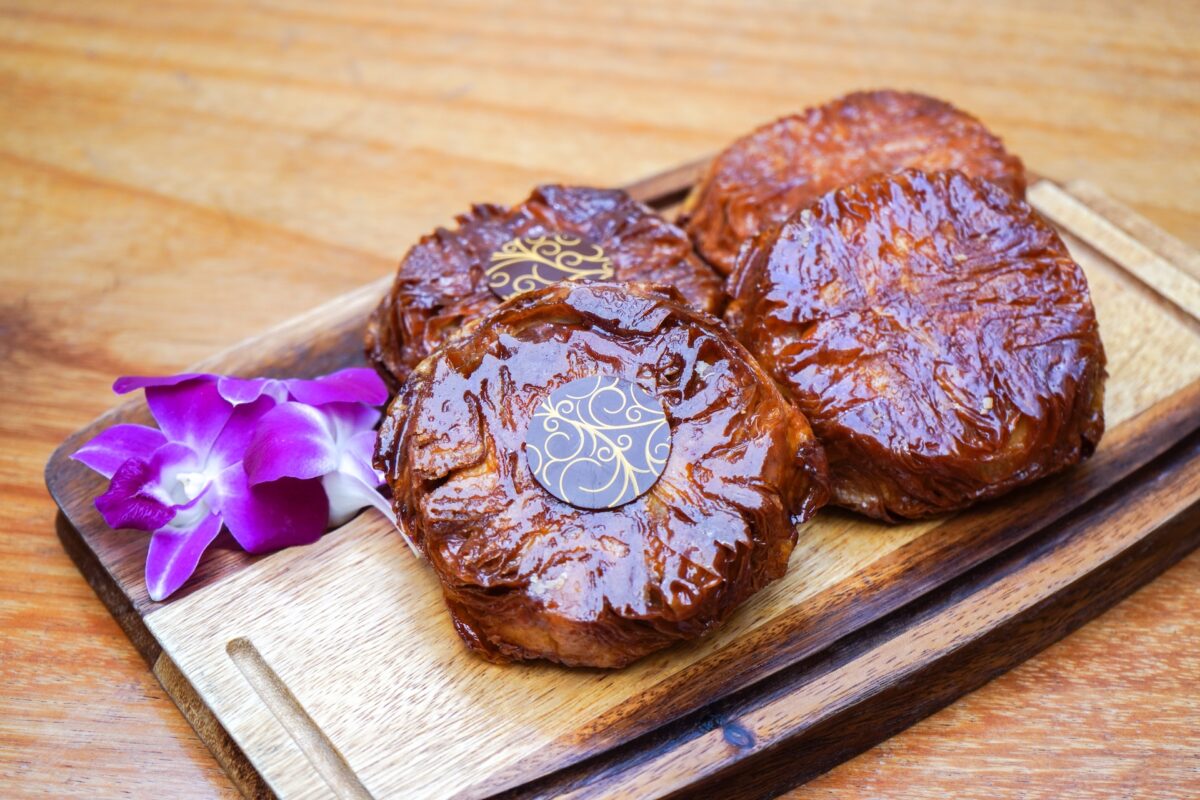 A cutting board with glossy discs of pastry and flowers on the side.