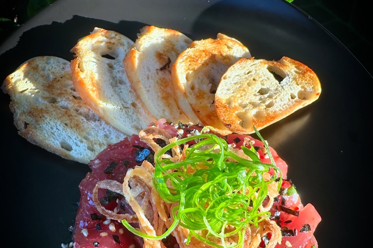 Slices of toasted baguette with some poke topped with furikakeand seaweed.