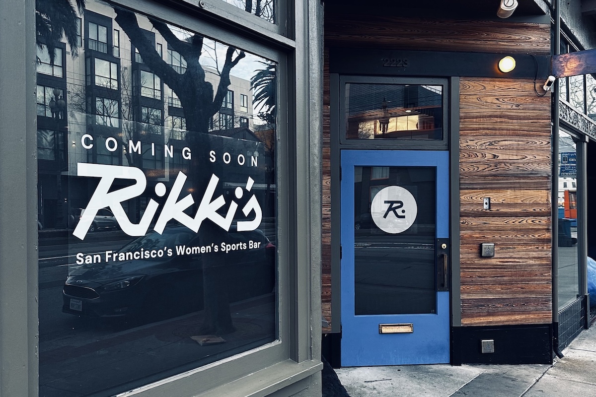 The entrance to a restaurant with a blue bordered door and a window with a logo reading "Rikki's" on it.