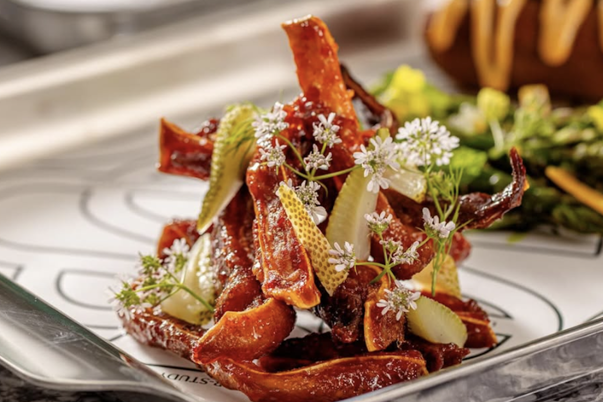 A tangle of red strips topped with slices of green fruit and tiny flowers for garnish.