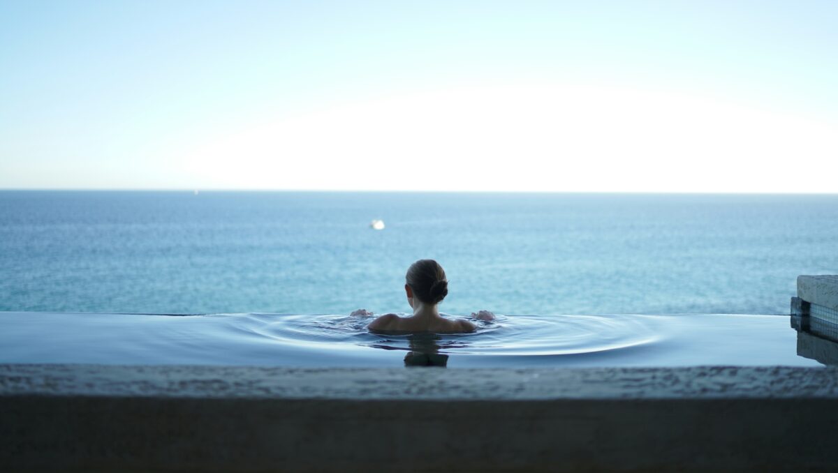woman in pool overlooking ocean relaxing