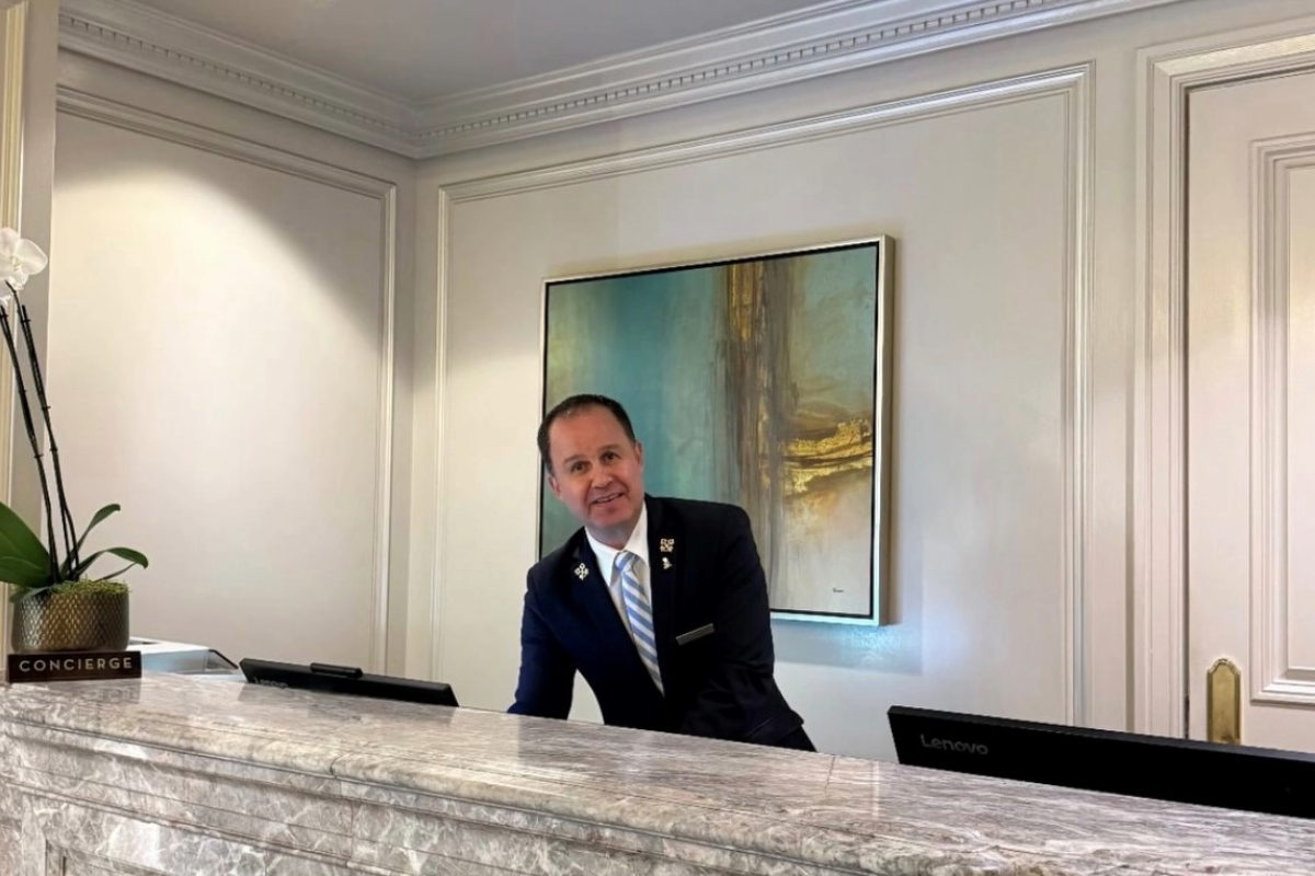 Juan Manuel Marquez at the Ritz-Carlton concierge desk, smiling in his suit and striped tie.