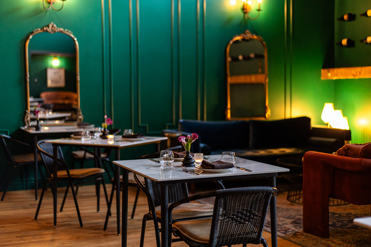 Interior view of a restaurant with vibrant green walls and a table ready for guests.