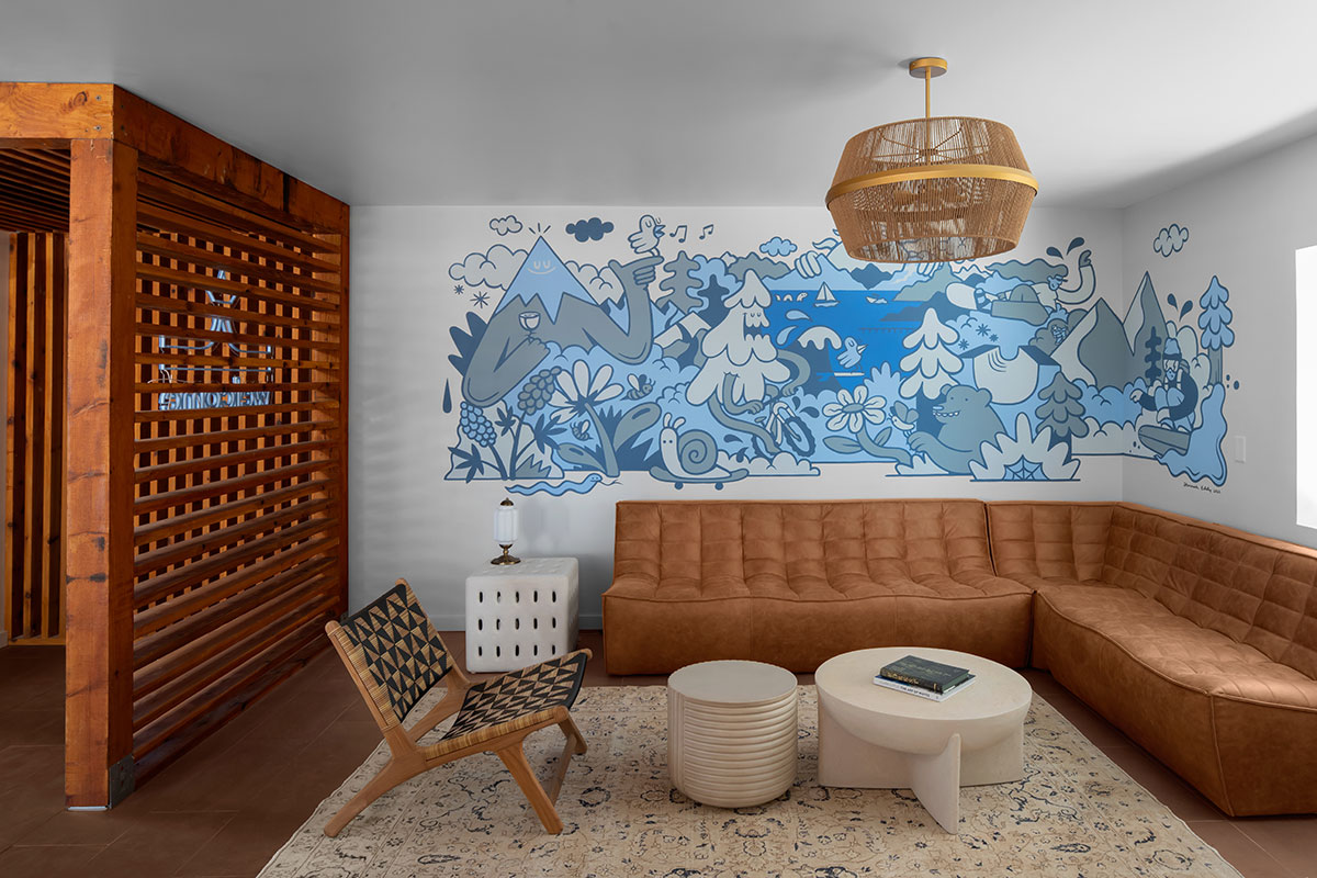 A cozy living room featuring a couch, coffee table, and a vibrant wall mural.