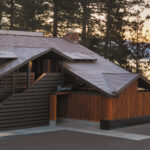 Contemporary house with a wooden roof and a driveway, set in a landscaped environment.