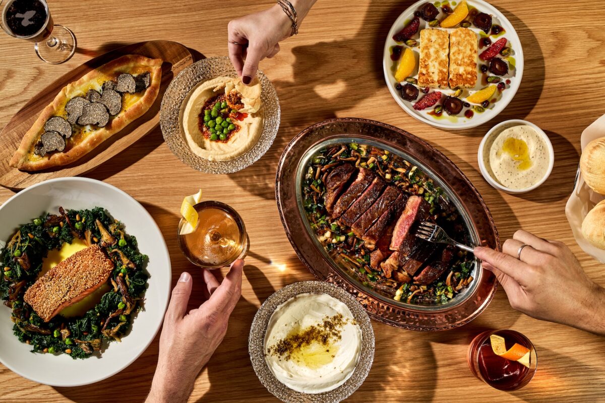 An aerial shot people reaching for different dishes of nicely plated food.