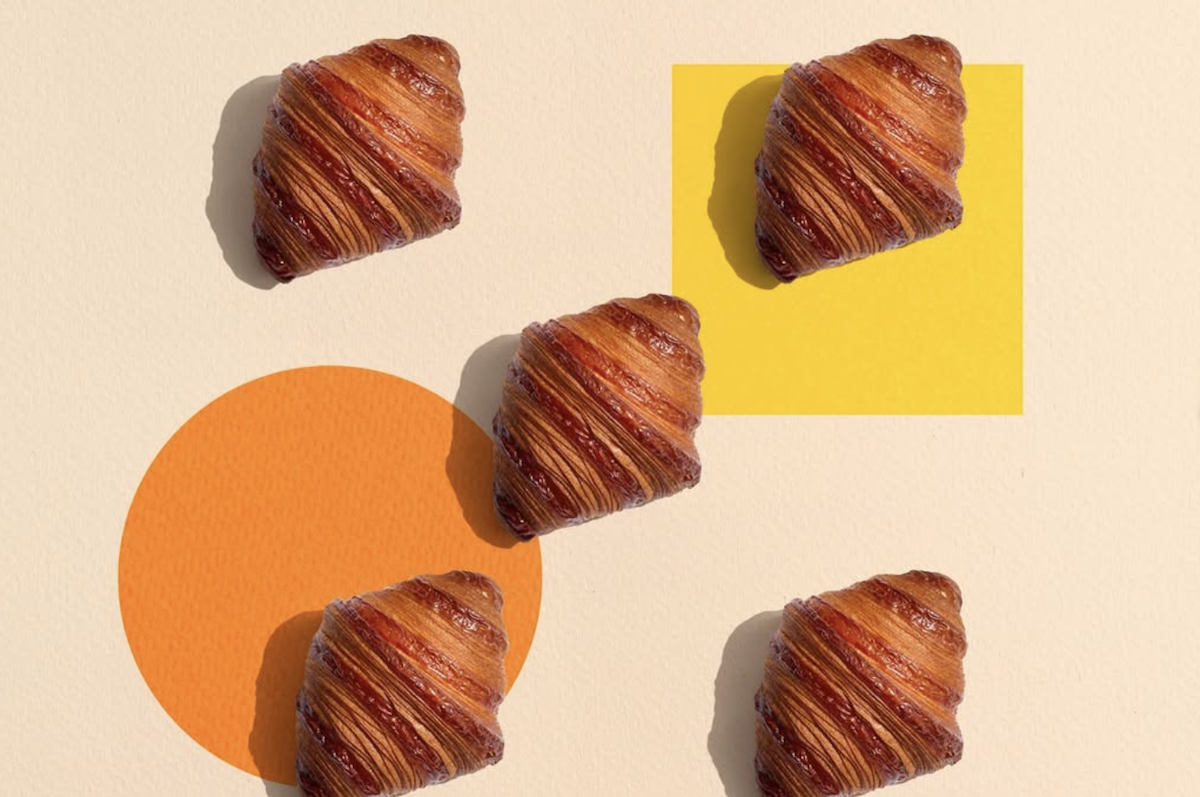 Five croissants are oriented on a plain background with orange and yellow shapes.