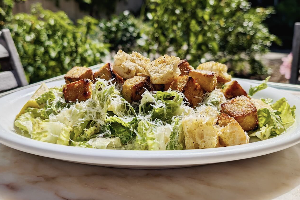 A plate with a Caesar salad topped with parmesan and croutons.