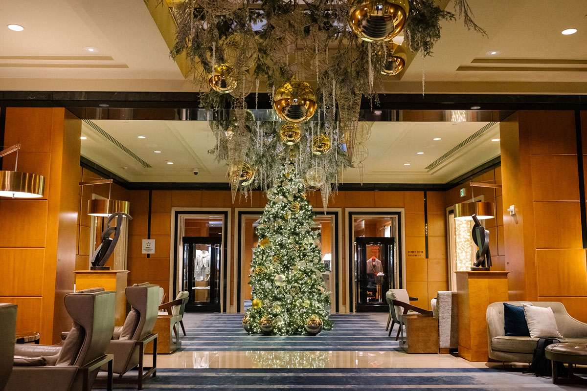 The hotel lobby features a tall Christmas tree adorned with lights and ornaments, creating a warm holiday atmosphere.