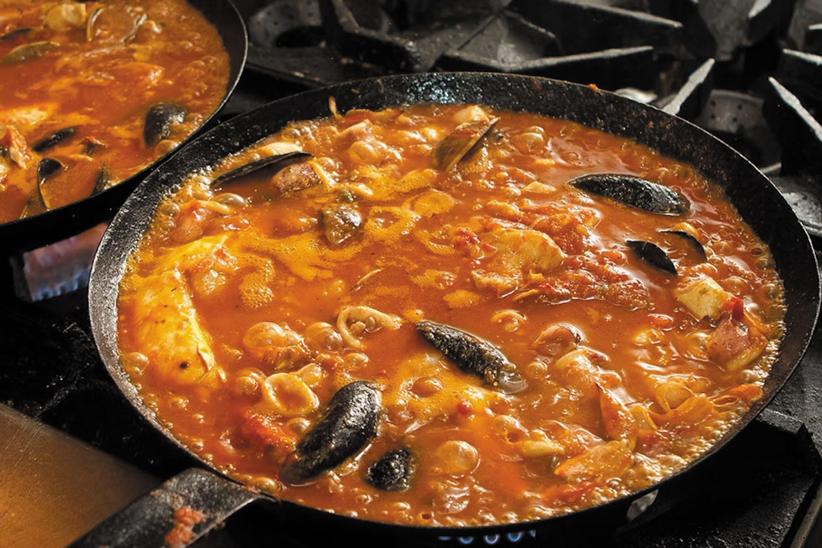 A pan full of seafood and pasta is placed on an oven, highlighting a delicious blend of flavors and textures.