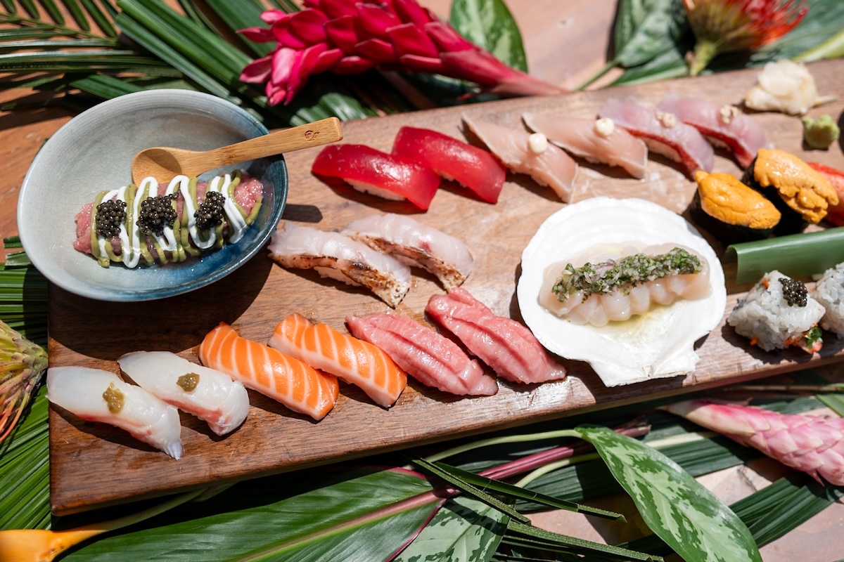 An aerial shot of a wooden board with various sushi cuts.