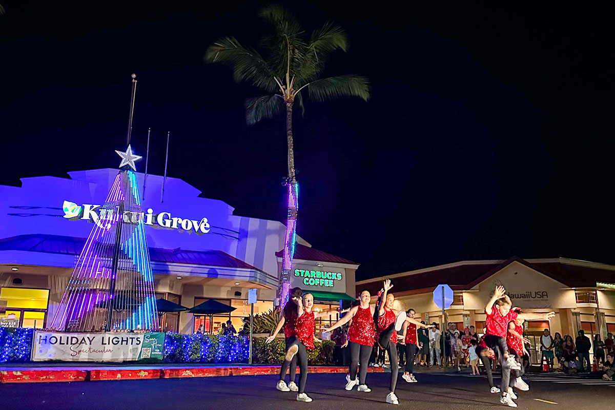 A vibrant group of dancers entertains a crowd in front of a store, highlighting their choreography and enthusiasm.