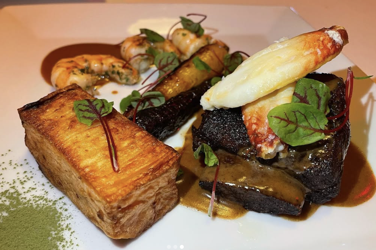 A fine dining plate of food, with leaves and sauce for garnish.