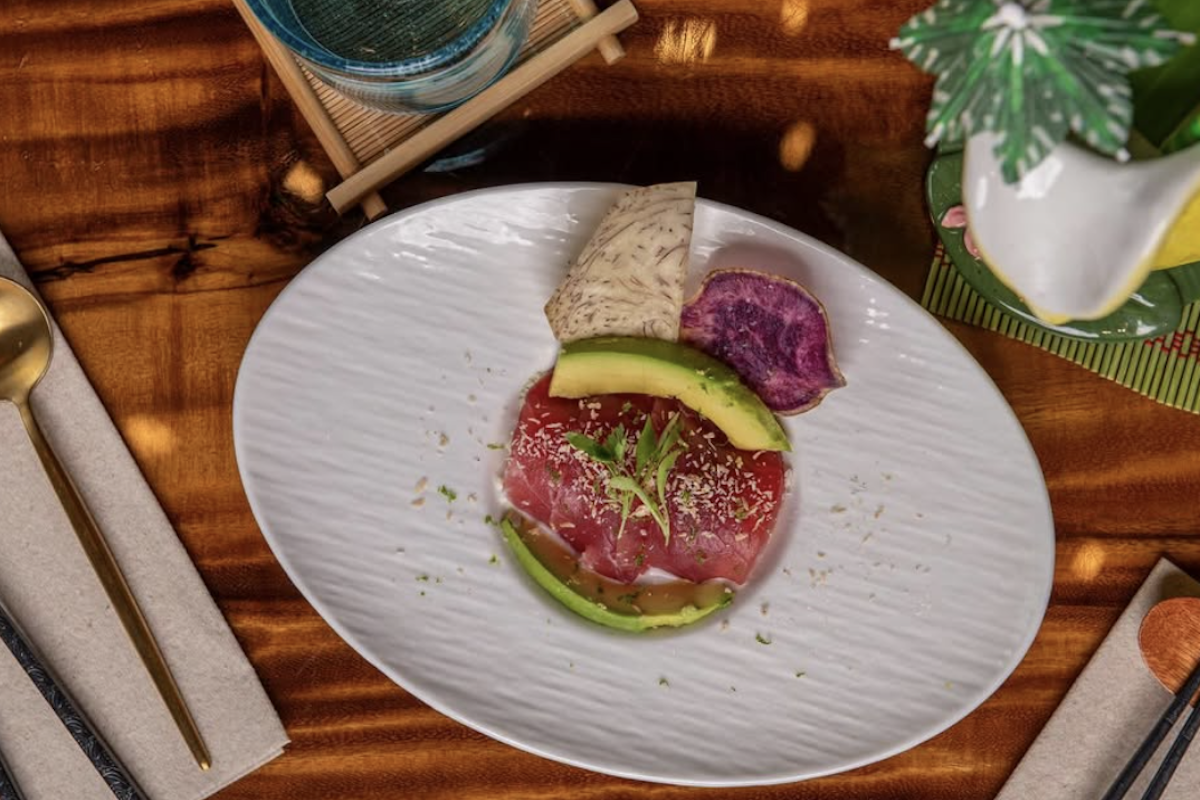 An aerial shot of a cut of fish with avocado and root veggies on the side.