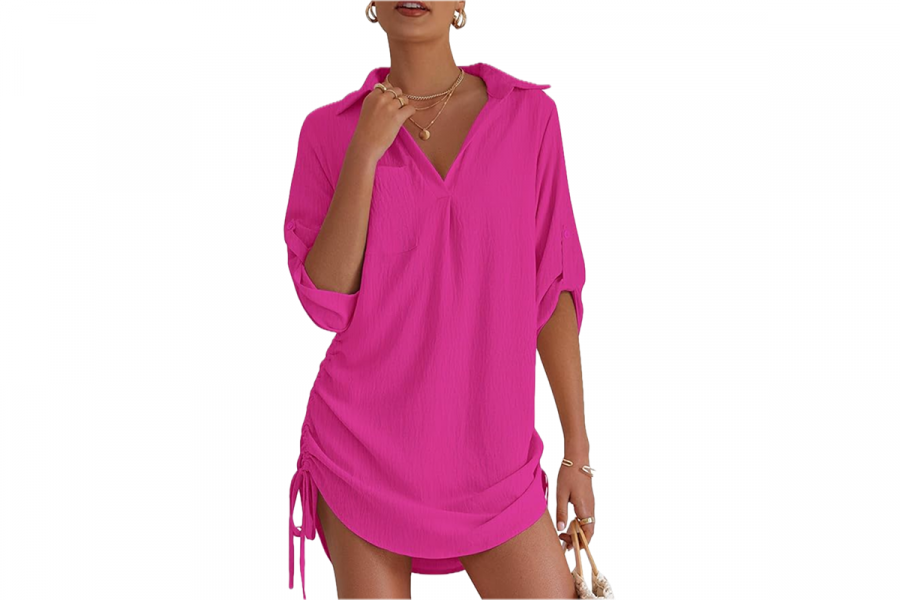 A woman wearing a bright pink shirt dress with drawstring sides.