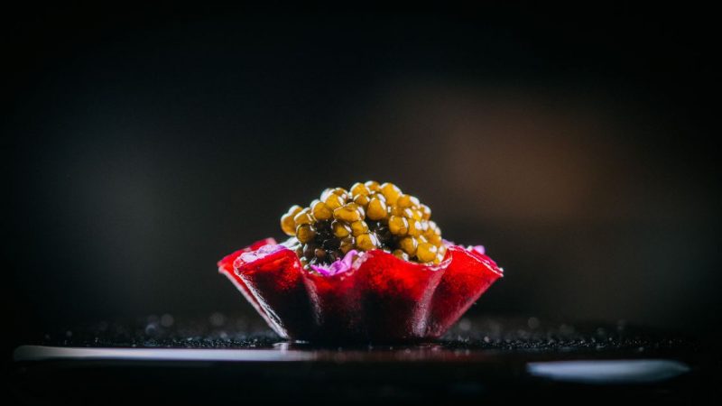 A small cup of caviar on a sleek black table at Addison San Diego