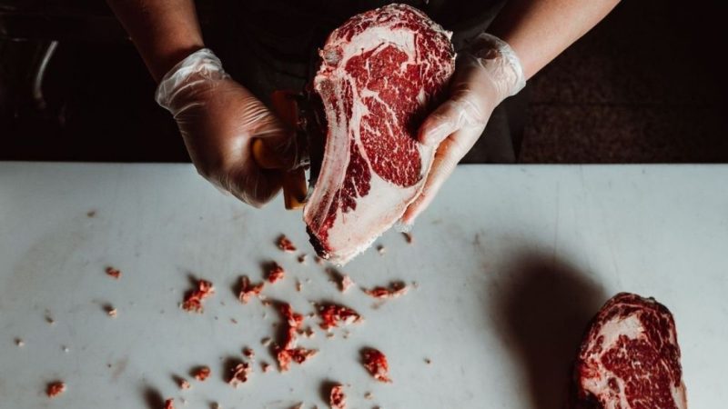 A butcher cuts from a chunk of meat at Born + Raised restaurant