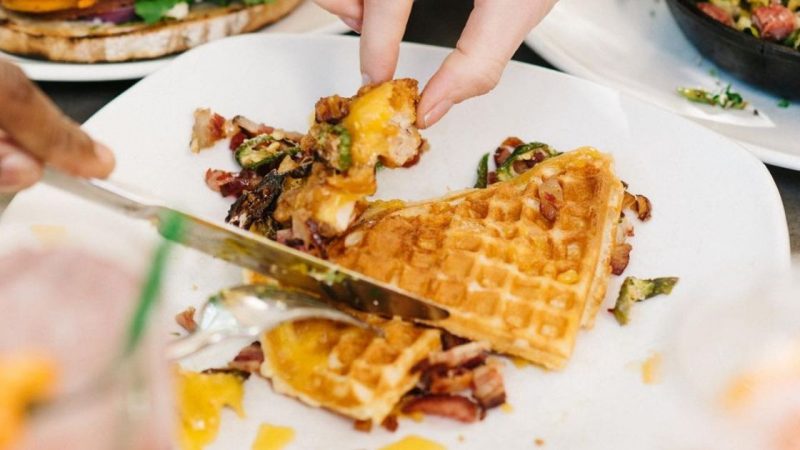 A person cuts into chicken and waffles at Cheeky's in Palm Springs breakfast