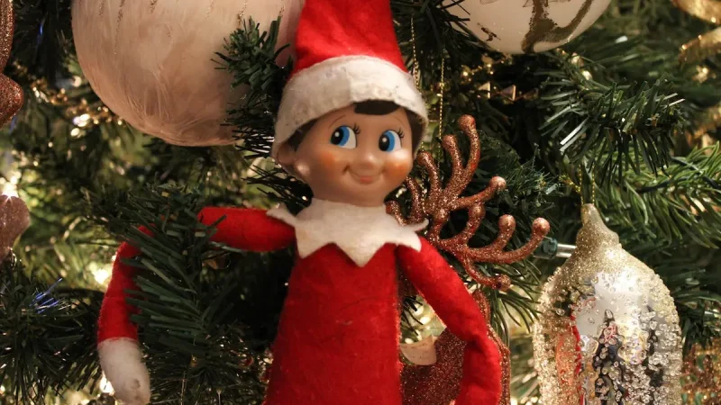 Elf on a shelf nestled in Christmas tree